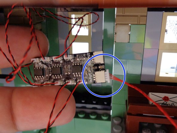 Take one of the red 12&quot; (30.4cm) 3-wire cables from Bag 1 and connect one end to the large plug on the BRANCH09X adapter board labeled INPUT as shown by the blue circle in the second photo.