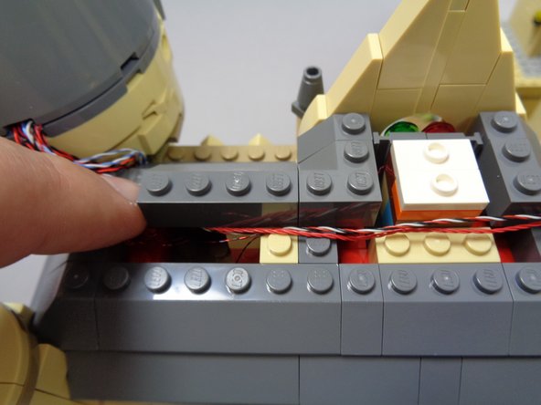 As shown in the first photo, remove several layers of roof pieces to make room for running the red and red/white/black wires toward the other tower (on the right in the first photo).