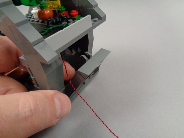 As shown in the second and third photos for this step, gently press with your finger on the side of the house (behind where the blackboard was mounted) so the side of the house tilts outward.