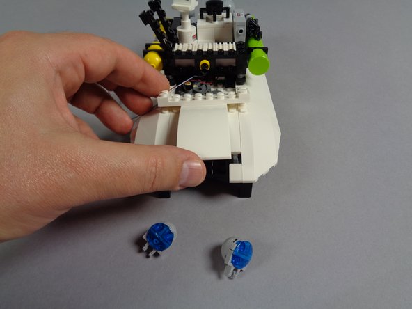 As shown in the photos for this step, carefully remove the two rear blue roof lights, and then remove the center curved roof slope panel.