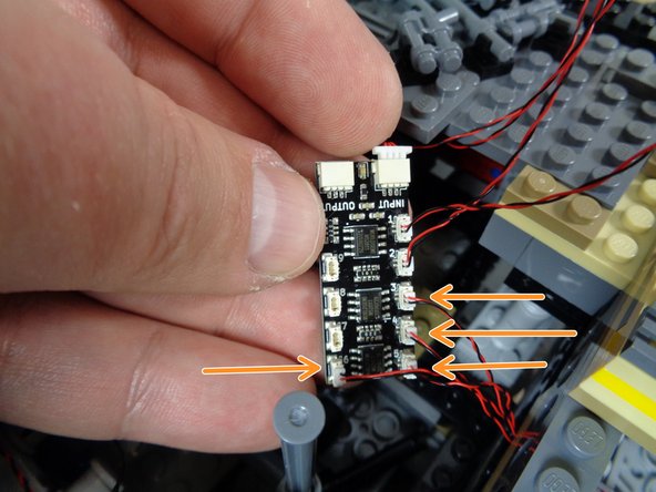 As shown by the orange arrows in the photo for this step, connect the four cockpit control panel light wires to plugs #3, #4, #5, and #6 on the second BRANCH09X adapter board.