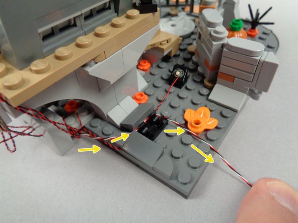 As shown by the yellow arrows in the first photo for this step, route the 3-wire connecting cable around the tree's base hinge.