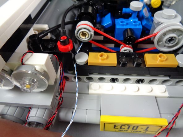 As shown in the third photo for this step, re-attach the round tile to hold the speedometer light wire in place.