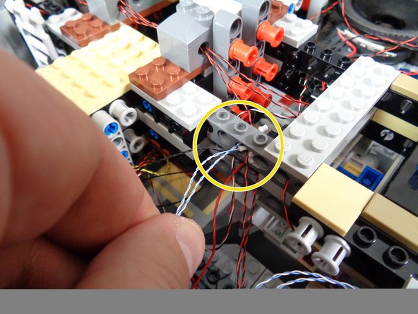 As shown in the second and third photos, pull the laser light wires up through the center of the Falcon and pass the wires through the stud holes in the Technic bricks at the center of the Falcon core.