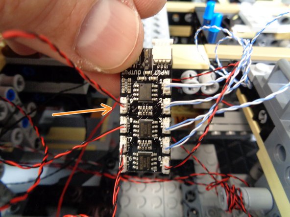 As shown in the second photo, re-attach the corner tile and run the light wire underneath the door frame and into the right rear area near the BRANCH09X adapter board.