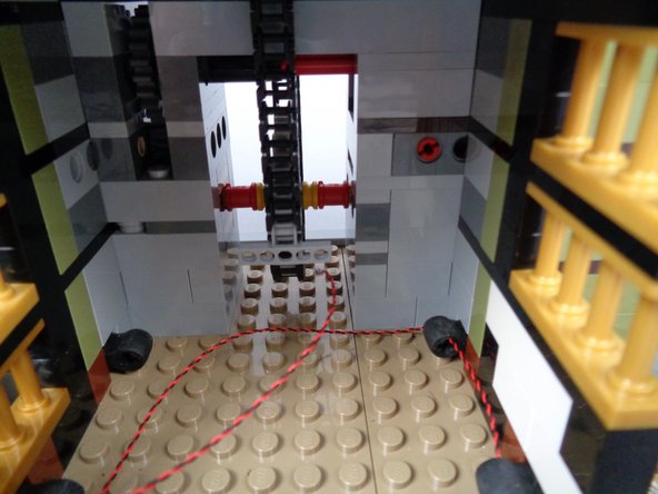 As shown in the first photo for this step, pass the wire through the back of the elevator shaft.