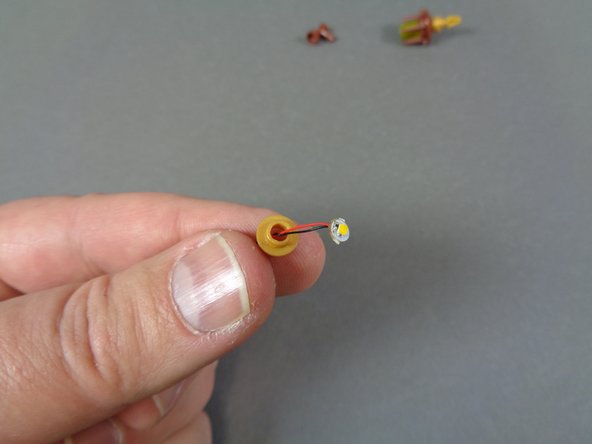 As shown in the third photo, feed the LED light wire through the hole in the round 1x1 gold plate.