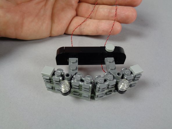 As shown in the second photo for this step, carefully re-attach the strobe mount assembly to the main grille.