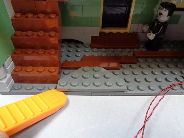 As shown in the first and second photos, remove the dark bluish gray plate and brown tile from the floor.