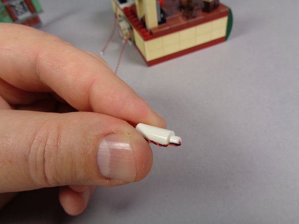 As shown in the second photo, carefully bend the light wires at the bottom of the candles so the wires are tight against the small white pins on the candle bottoms.