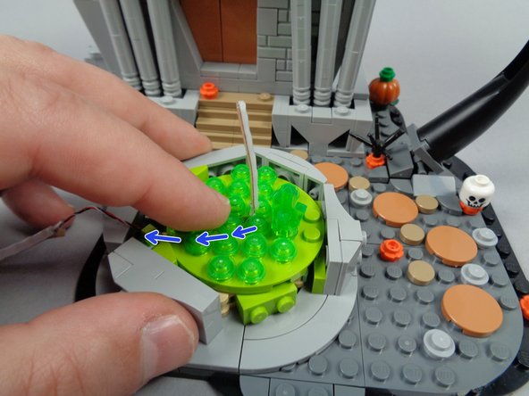 As shown in the third photo for this step, re-attach the fountain base with the short light strip segment sticking up through the center hole in the base plate.