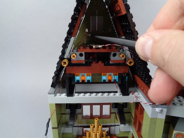 As shown in the third photo for this step, you can use the tweezers if needed to help pull both wires up into the top roof space.