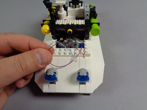 As shown in the third photo for this step, you should now have wires for two lights coming out the back of the top roof assembly: one red and black wire for the roof strobe and one blue and white wire for the red roof light.