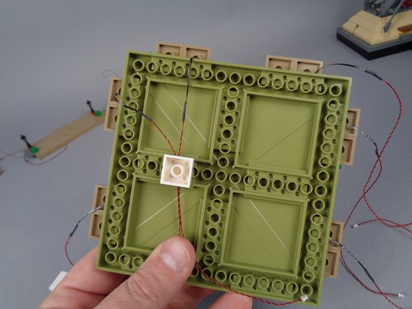 In order to prevent damage to the LED light wires when re-attaching the large plates, you can use the two white 2x2 bricks you removed in Step 47 to hold the wires, as shown in the photo for this step.