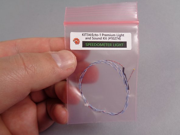 Take the small pink bag labeled &quot;Speedometer Light&quot; out of the larger &quot;Roof Parts&quot; bag, and carefully remove the speedometer light assembly.