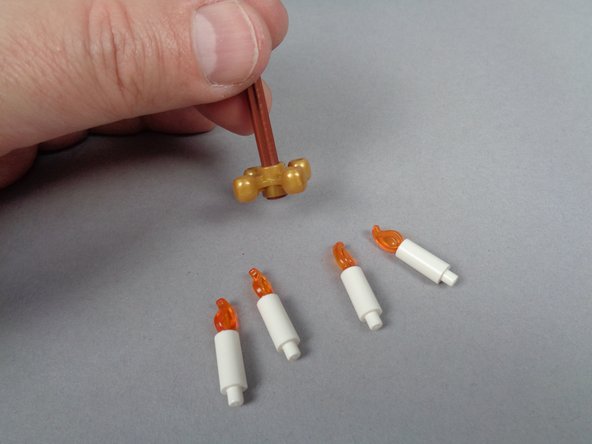 As shown in the photos for this step, remove the chandelier from its holder, and remove the four candles from the 4-hole gold base.