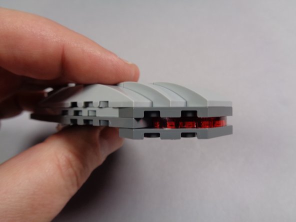 As shown in the second photo for this step, carefully press the pre-lit eye section into the head.