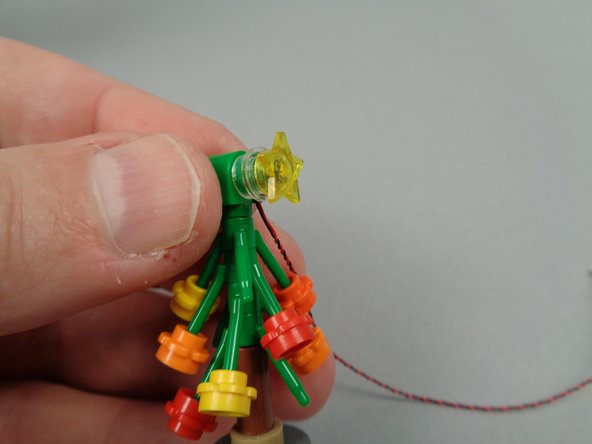 As shown in the first photo for this step, press the star light assembly back onto the top of the tree.