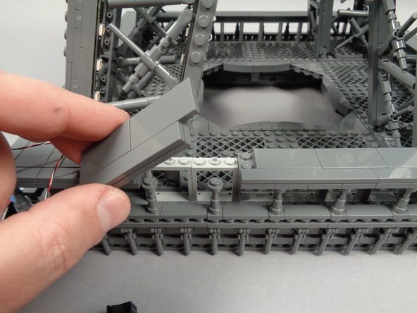 Tuck the adapter board into the base of the first pillar, then remove a section from the outer frame as shown in the first photo for this step.