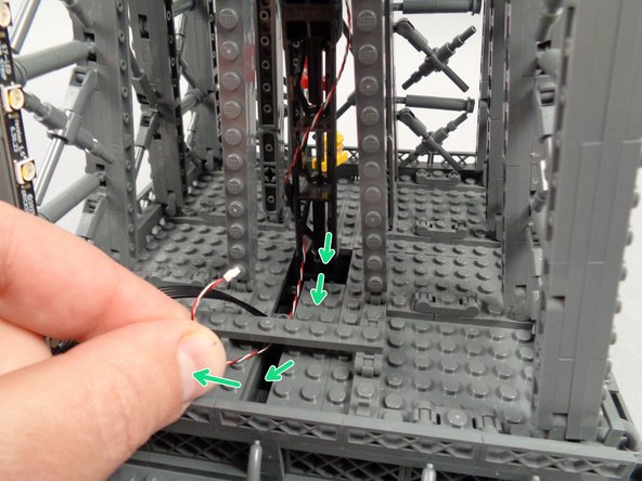 As shown by the green arrows in the first photo for this step, loop the control wire underneath the 1x8 support plate.