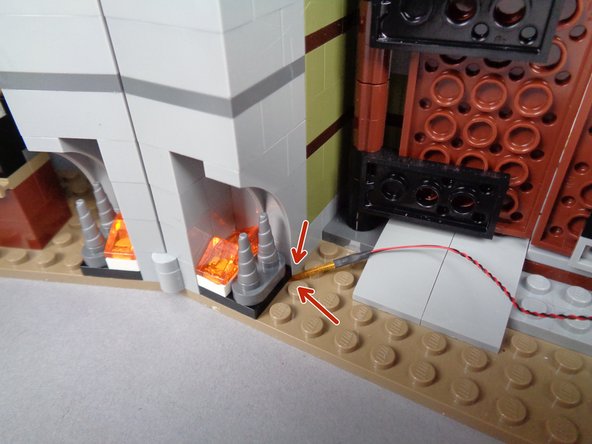 Making sure the flexible wire runs between and not on top of any studs, carefully re-attach the fireplace section in the mansion as shown in the third photo for this step.