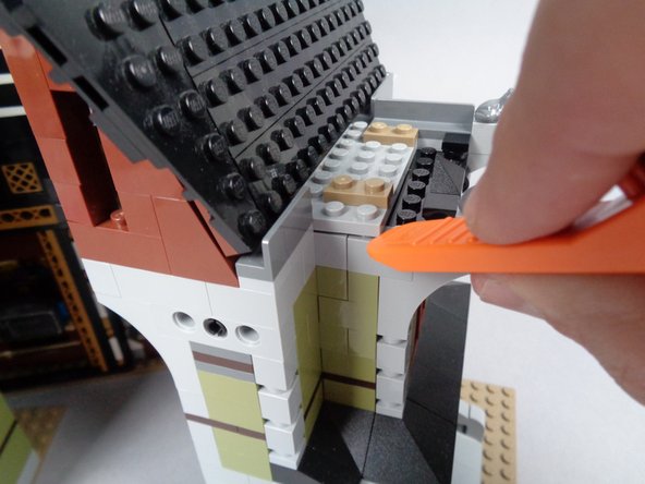 As shown in the two photos for this step, use the LEGO brick separator that came with your Haunted Mansion kit to pry up the baseplate above the window, then remove the 1x2 brick at the top of the wall.