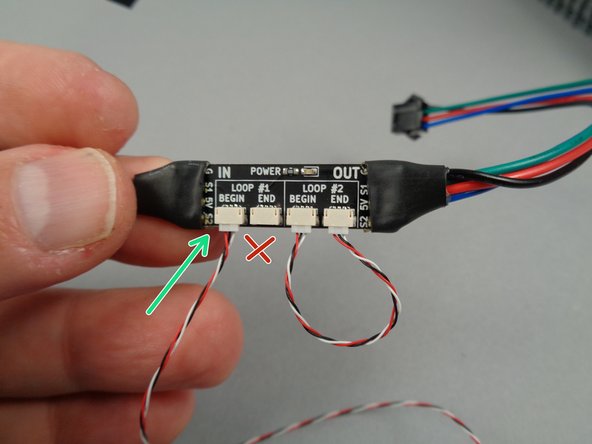 As shown by the green arrow in the first photo for this step, take one of the 3-wire control cables and connect it to the plug labeled BEGIN.  Do not connect anything to the END plug at this time.