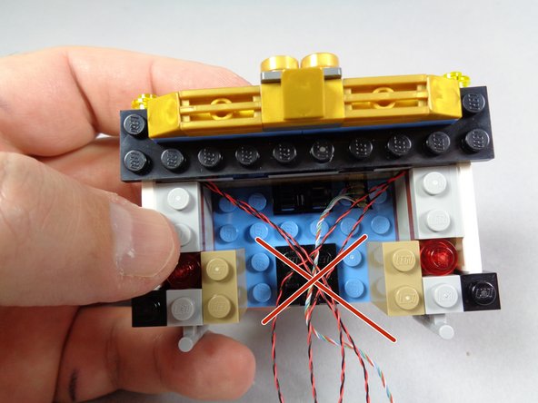 The green arrows in the first photo for this step show the correct way for the wires to pass, and the red square shows the area to keep wires out.