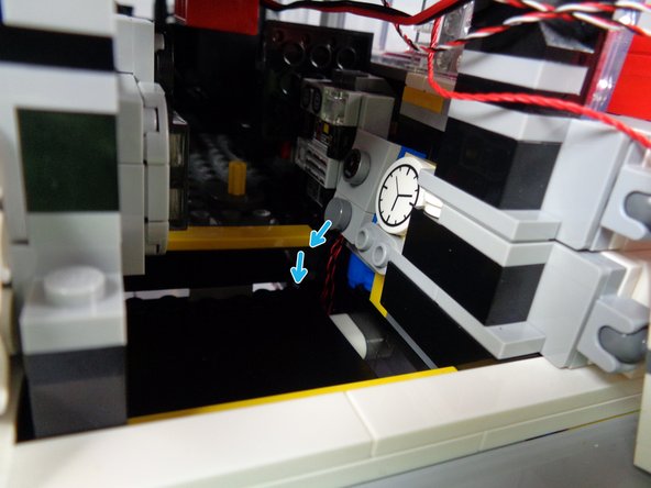 As shown by the blue arrows in the third photo, pass the wire down to the underside of the car, following the same path as the other two tail light wires.