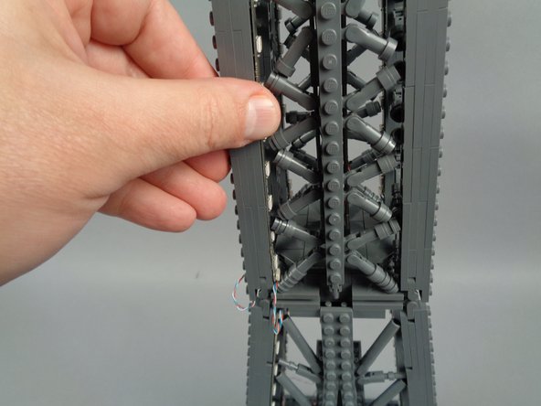 As shown in the photos for this step, attach the top of strip #2 to the tower frame, and re-position brace elements as needed to make room for the LED lights and strip.