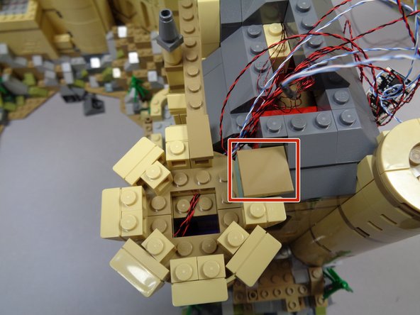 As shown by the red square in the second photo, re-attach the dark tan 2x2 tile you removed earlier so it holds the tower top to the main roof (one stud of the tile will hang over the tower edge).