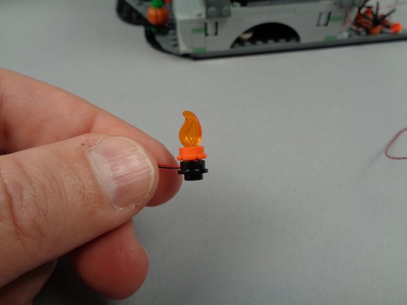 As shown in the third photo for this step, re-attach the top section of both torches on top of the round black plates with lights inside.