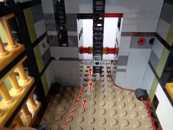 As shown by the red arrows in the first photo for this step, pass the candle light wire out the back of the elevator shaft.