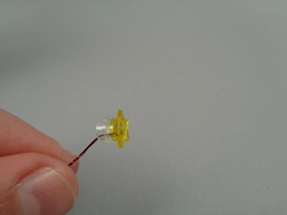 As shown in the second photo for this step, press the transparent yellow star on top of the LED light and on top of the transparent plate.  This will hold the LED light in place.