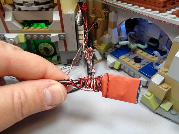 As shown in the photos for this step, you can coil extra wires around the sound module (if included in your kit) and the RF remote receiver module.  Wires and modules can also be tucked in the gap between the main castle and the main tower as shown in the third photo.