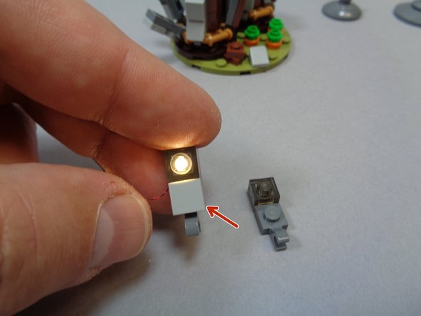 As shown in the first photo, take the light bluish gray 1x1 LEGO® tile and switch it onto the pre-lit replacement window.