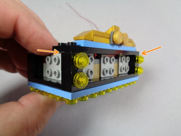 As shown by the orange arrows in the second photo, position the two stacks of front lights so they are held in place by the top plate.