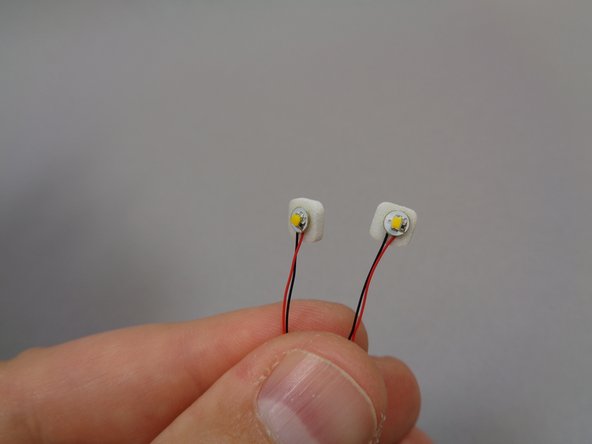 As shown in the first photo, take two warm white lights from Bag 9 and attach a small sticky square to the back of each light.