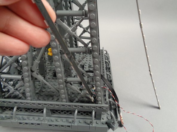 Remove the backs of the sticky dots on the first light strip (connected to plug #1 of the adapter board), and attach the strip to the tower frame as shown in the photos for this step.