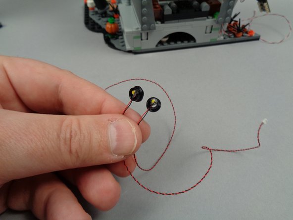 As shown in the third photo for this step, re-attach the top section of both torches on top of the round black plates with lights inside.