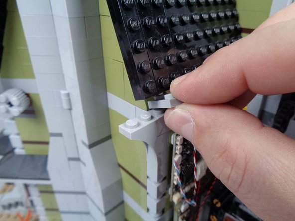 As shown in the photos for this step, remove several pieces from the back side of the mansion wall.  This is to make room for passing the wire for the green LED light.