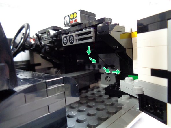 The green arrows in the second photo show how the wire for the speedometer light should pass under the dashboard and through the hole in the Technic brick.