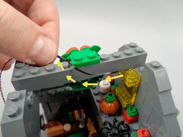 As shown by the yellow arrows in the second photo for this step, run the LED Light wire toward the back, looping it up and over the top of the cross-beam.