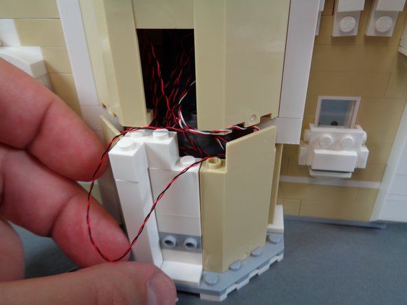 Continue carefully re-assembling the castle front as shown in the photos for this step, making sure not to pinch or pull any wires.