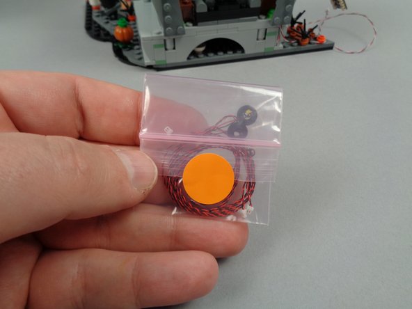 As shown in the first photo for this step, take the small bag with the orange dot from your larger Bag 3 and remove the two LED lights mounted inside the black 1x1 round plates (see photo #2).
