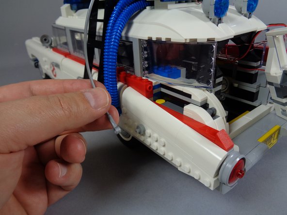 As shown in the photos for this step, disconnect the hose on the left side of the vehicle and remove the same parts of the vehicle frame as you did for the right side.