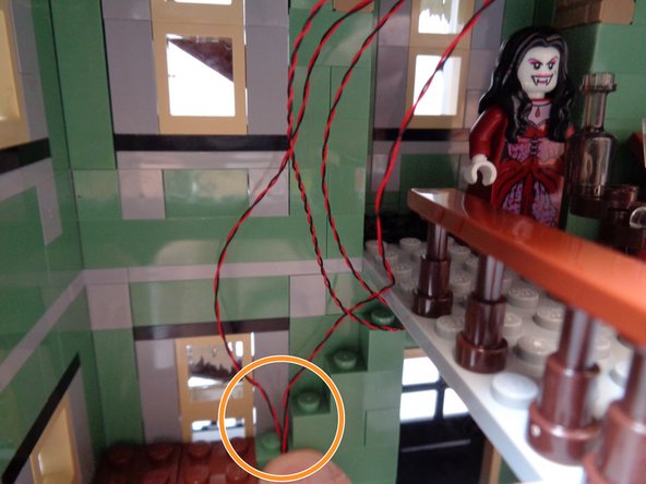 As shown by the orange circle in the first photo, take the two fireplace light wires and hold them along the wall where the staircase turns the corner.