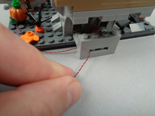 As shown in the first photo for this step, pass the LED light wire through the hole in the base you built earlier.