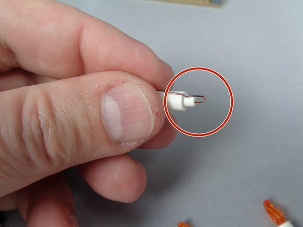 As shown by the red circle in the second photo for this step, carefully bend the wire around the bottom of each of the Brickstuff candles, making sure to leave a little extra wire on the bottom.  This extra wire is critical to allowing you to install the candles without breaking the LED light inside the candle.