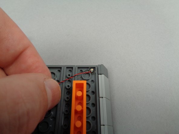 As shown in the first photo for this step, mount the first green roof light at the top right corner of the right roof section.